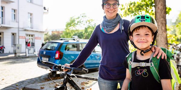 Eine Frau mit einem Fahrrad und ein kleiner Junge lächeln in die Kamera